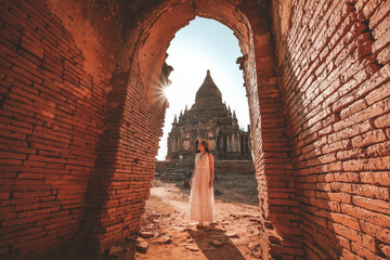 A young female traveler walks along the road towards an ancient temple in Bagan, Myanmar.