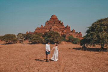 A traveling couple walks along the road towards an ancient temple in Bagan, Myanmar.