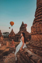 A young woman stands and watches a balloon float at Bagan Temple in the Burmese Archaeological Zone...