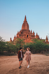 A traveling couple walks along the road towards an ancient temple in Bagan, Myanmar.