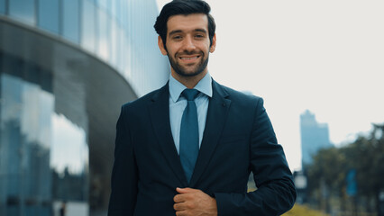 Professional businessman standing at city or park. Smiling project manager looking at camera while...