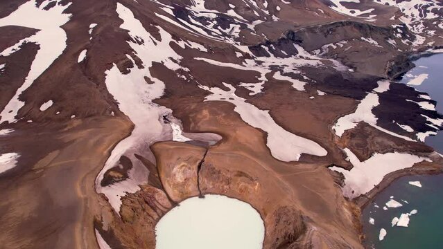 Epic Aerial View of Two Adventure Hikers Walking on Rim of Crater Lake Caldera Iceland Water With Snow and Emerald Pool. In Askja Iceland Region Hikers Are Small in Large Wide View