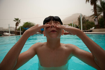 Boy with glasses swims in the pool