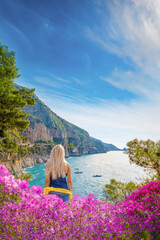 Positano, Italy - A blonde haired woman enjoys a view of the rocky coastline of the Amalfi Coast, Italy.