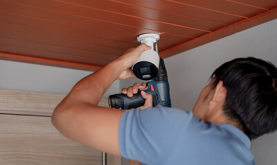 A technician installs a CCTV camera in a modern apartment. - 790577108