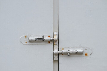 Two haspels on white wooden doors.