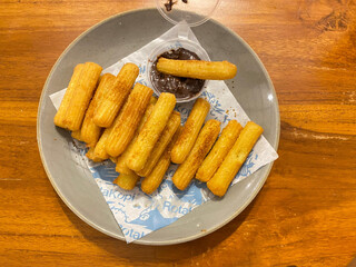 close up hand hold churros with chocolate sauce