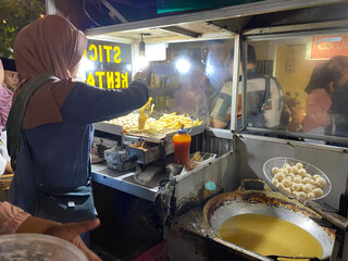 woman street vendor selling stick kentang and cimol at the night market