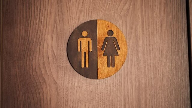 close up in a professional kitchen of a wooden toilet door with round defining icon