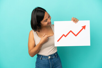 Young mixed race woman isolated on blue background holding a sign with a growing statistics arrow...