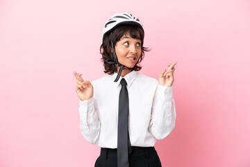 Young girl person with a bike helmet isolated on pink background with fingers crossing