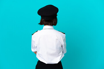Young airplane pilot over isolated blue background in back position