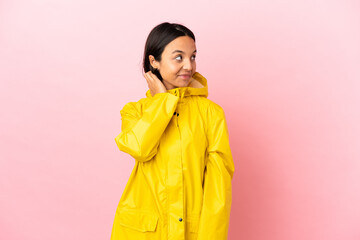 Young latin woman wearing a rainproof coat over isolated background thinking an idea