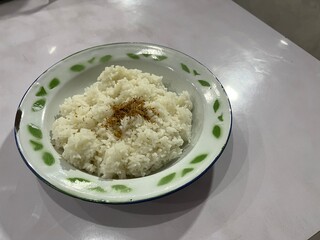 A plate of white rice served with sprinkle of Serundeng which is made from grated and roasted coconut on top