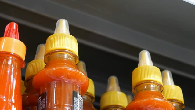 Close-up of a male hand taking a hot sauce bottle