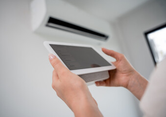 Young woman operates wireless aircon system in a modern apartment.