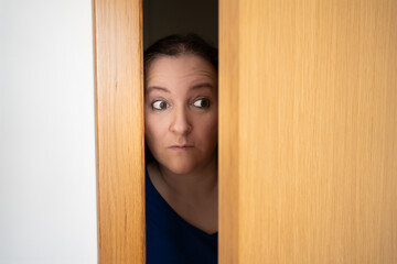 Cropped shot of woman spying and entering through the door as concept of nosy woman - obrazy, fototapety, plakaty