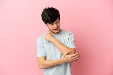 Young Russian man isolated on pink background with pain in elbow
