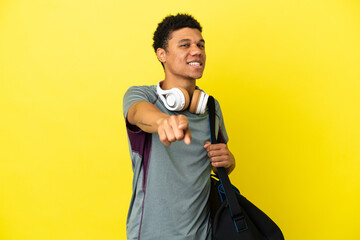 Young sport African American man with sport bag isolated on yellow background points finger at you with a confident expression