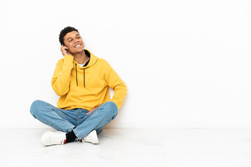 Young African American man sitting on the floor isolated on white background thinking an idea