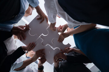 Below view of diverse corporate officer workers collaborate in office connecting puzzle pieces as...