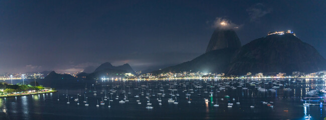 Panoramic Night View of Sailboats and City Lights by the Sea