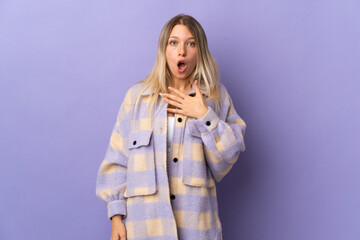 Young blonde woman isolated on purple background surprised and shocked while looking right