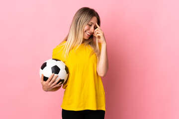 Young football player woman isolated on pink background laughing