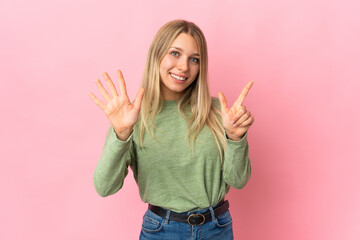 Young blonde woman isolated on pink background counting seven with fingers