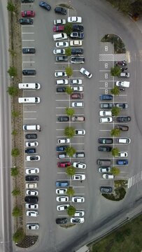 Busy large modern carpark with symmetrical roads rows of parking bays lots of symmetry and colours aerial view from drone up above looking down.