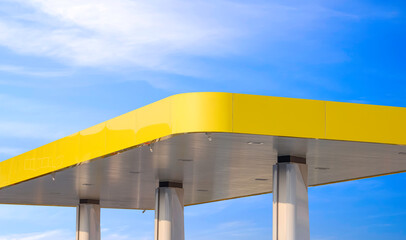 Modern yellow canopy roof of outdoor distribution service point with columns of gas station against...