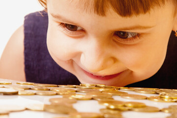I love money! Happy beautiful little business child girl looking at coins as a symbol of love for money. - 790641153