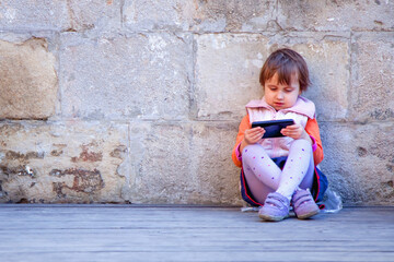 Little beautiful child girl using smartphone as symbol of work or study. Connect to the Internet with smartphone.  Copy space for text or design.