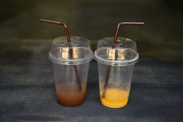 Plastic clear cup with dome lid  on  black table . plastic  glass of coffee and milk tea on a wood table . plastic cup waste and straw tube used .