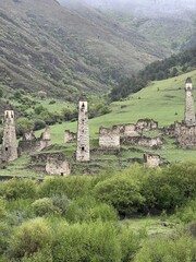 View of the medieval Targim tower complex in the Caucasus mountains surrounded by greenery. The Caucasus Mountains on a cloudy day in Ingushetia. Russia