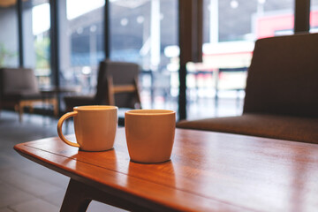 Two white cups of hot coffee on wooden table in cafe