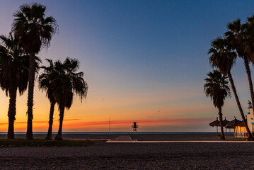 Sunrise on Poniente beach, Motril, Granada, with palm trees, a beach bar and a watchtower for bathers, Tropical coast.