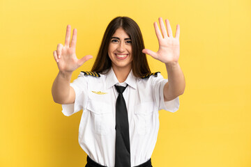Airplane pilot isolated on yellow background counting eight with fingers