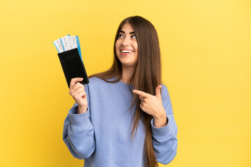 Young caucasian woman holding a passport isolated on yellow background intending to realizes the solution while lifting a finger up - obrazy, fototapety, plakaty