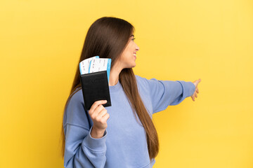 Naklejka premium Young caucasian woman holding a passport isolated on yellow background extending hands to the side for inviting to come