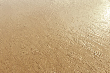 Golden Beige wet Sand texture as natural background. Close up sandy pattern from sea waves, light pastel color, minimal nature backdrop, beautiful beach. Summer, travel, spa and relaxation
