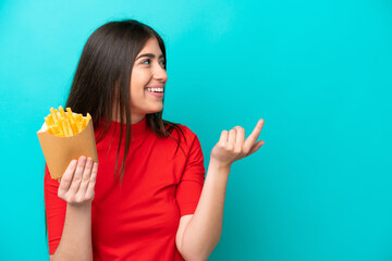 Young caucasian woman catching french fries isolated on blue background intending to realizes the...