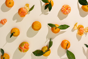 Fresh tangerines on beige background with sunlight shadows, minimal aesthetic citrus fruits as summer food pattern, healthy organic orange colored mandarin with green leaves top view, trend still life