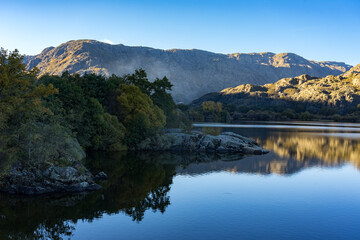 Fototapeta premium Sanabria Lake Natural Park in autumn at sunset with the mountains reflected in the water, Zamora, Castilla y León, Spain.