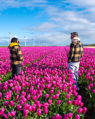 Two men standing tall amidst a sea of vibrant purple tulips in a stunning field in the Netherlands,...