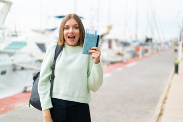Young pretty blonde woman holding a passport at outdoors with surprise and shocked facial expression