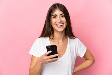 Young caucasian woman isolated on pink background using mobile phone - obrazy, fototapety, plakaty