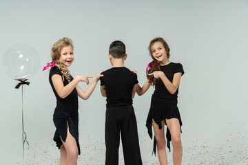 two curly-haired girls and boys engaged in ballroom dancing pose dressed in black