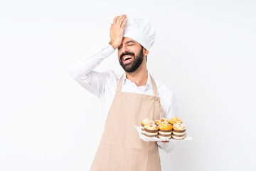 Young man holding muffin cake over isolated white background has realized something and intending the solution - obrazy, fototapety, plakaty