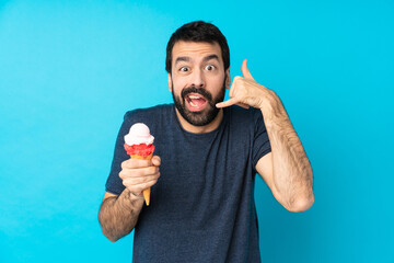 Young man with a cornet ice cream over isolated blue background making phone gesture and doubting